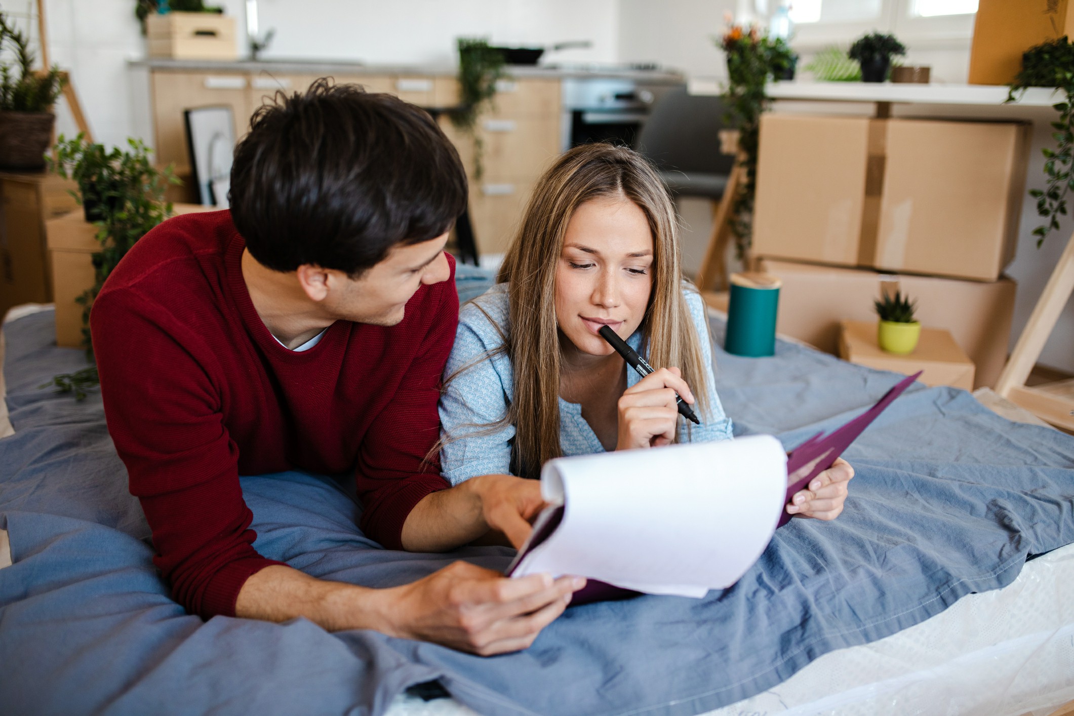 Preparing for Your Move Essential Steps A man and woman sit on a bed, reviewing documents together with focused expressions.