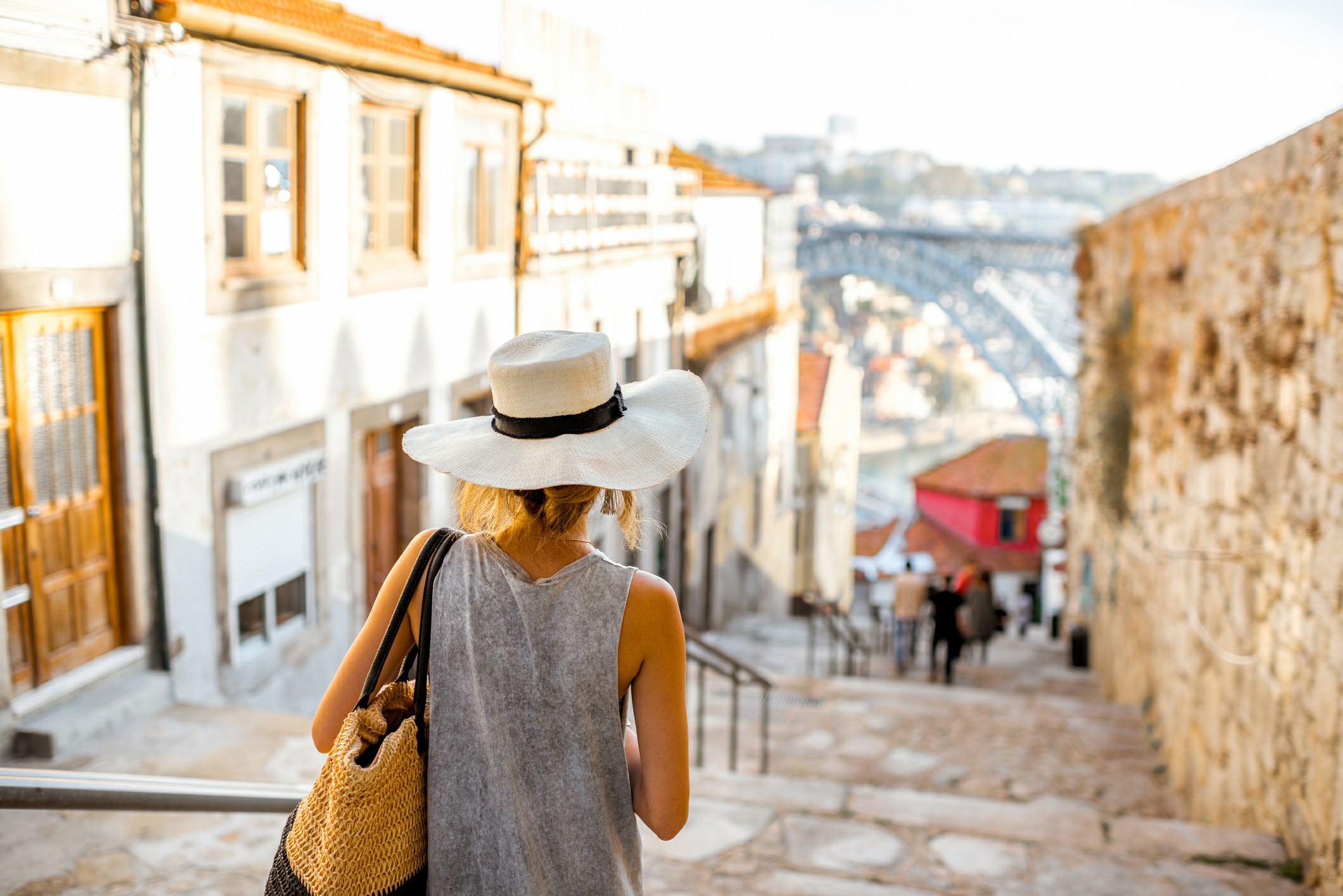 Settling Into Your New Home in Portugal A woman wearing a hat descends a stone stairway, showcasing her elegant style and the textured steps beneath her.