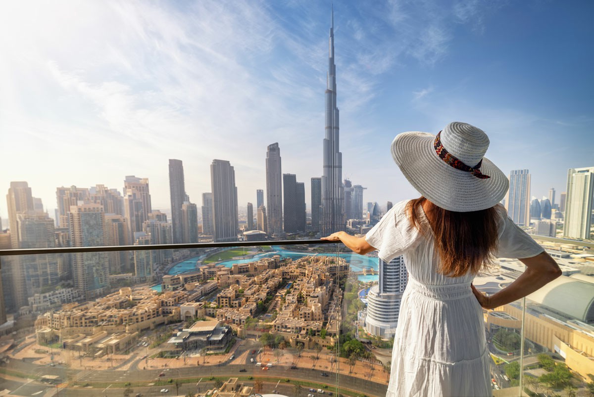 Common Challenges When Moving to Dubai (and How to Overcome Them) Woman in a white hat gazes at Dubai's skyline from the top of a tower, showcasing the city's modern architecture. Common Challenges When Moving to Dubai (and How to Overcome Them)