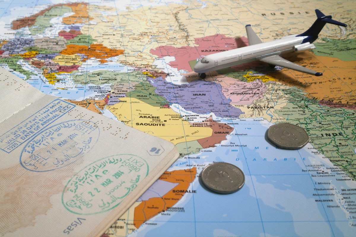Cost of Living: Melbourne vs. Dubai A passport, airplane, and coins are arranged on a world map, symbolizing travel and adventure; Cost of Living: Melbourne vs. Dubai