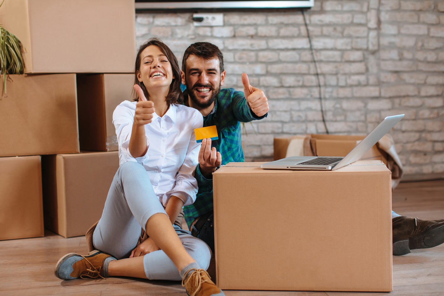 Get Started Today Request Your Free Quote from Chess Moving Two individuals sit on the floor with cardboard boxes nearby, focused on a laptop in front of them. Get Started Today Request Your Free Quote from Chess Moving