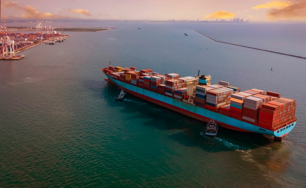 Shipping and Moving Your Belongings from Melbourne to Dubai A large container ship anchored in the water near a dock, with cargo containers stacked on its deck; Shipping and Moving Your Belongings from Melbourne to Dubai