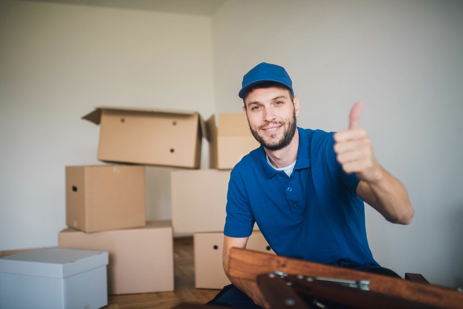 How To Choose A Trusted Moving Company A man wearing a blue shirt and hat shows a thumbs-up, expressing positivity and approval. Stress Free Moving. How To Choose A Trusted Moving Company