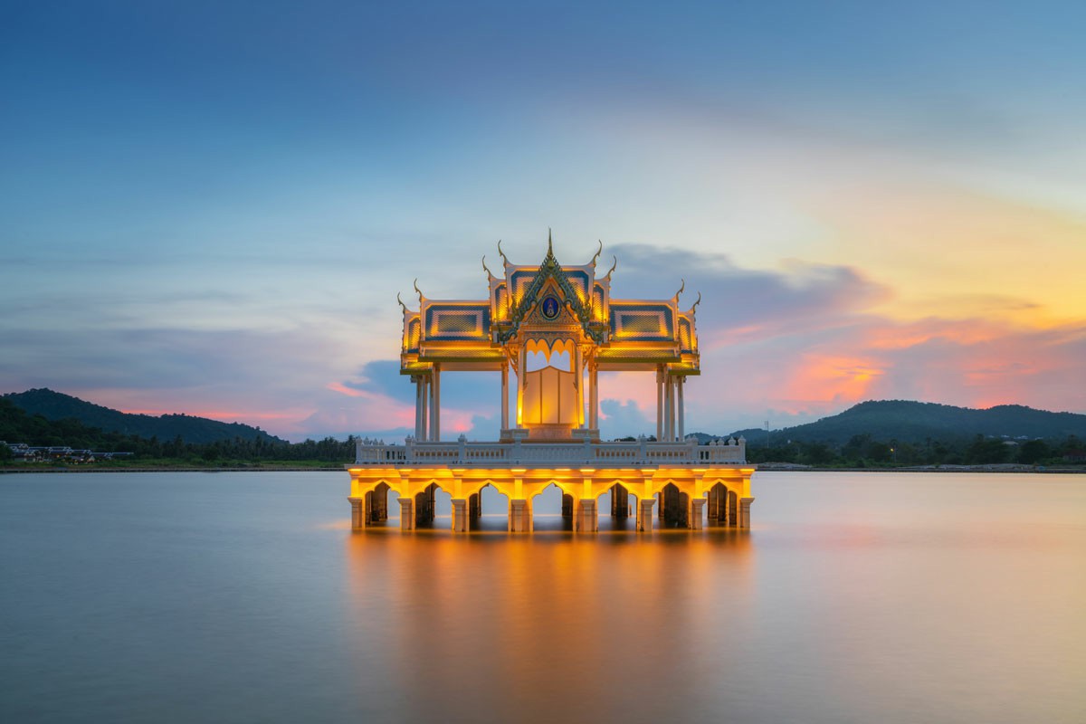 The Ultimate Guide to Moving from Brisbane to Thailand A serene temple stands in the center of a lake, illuminated by the warm hues of a sunset sky; The Ultimate Guide to Moving from Brisbane to Thailand