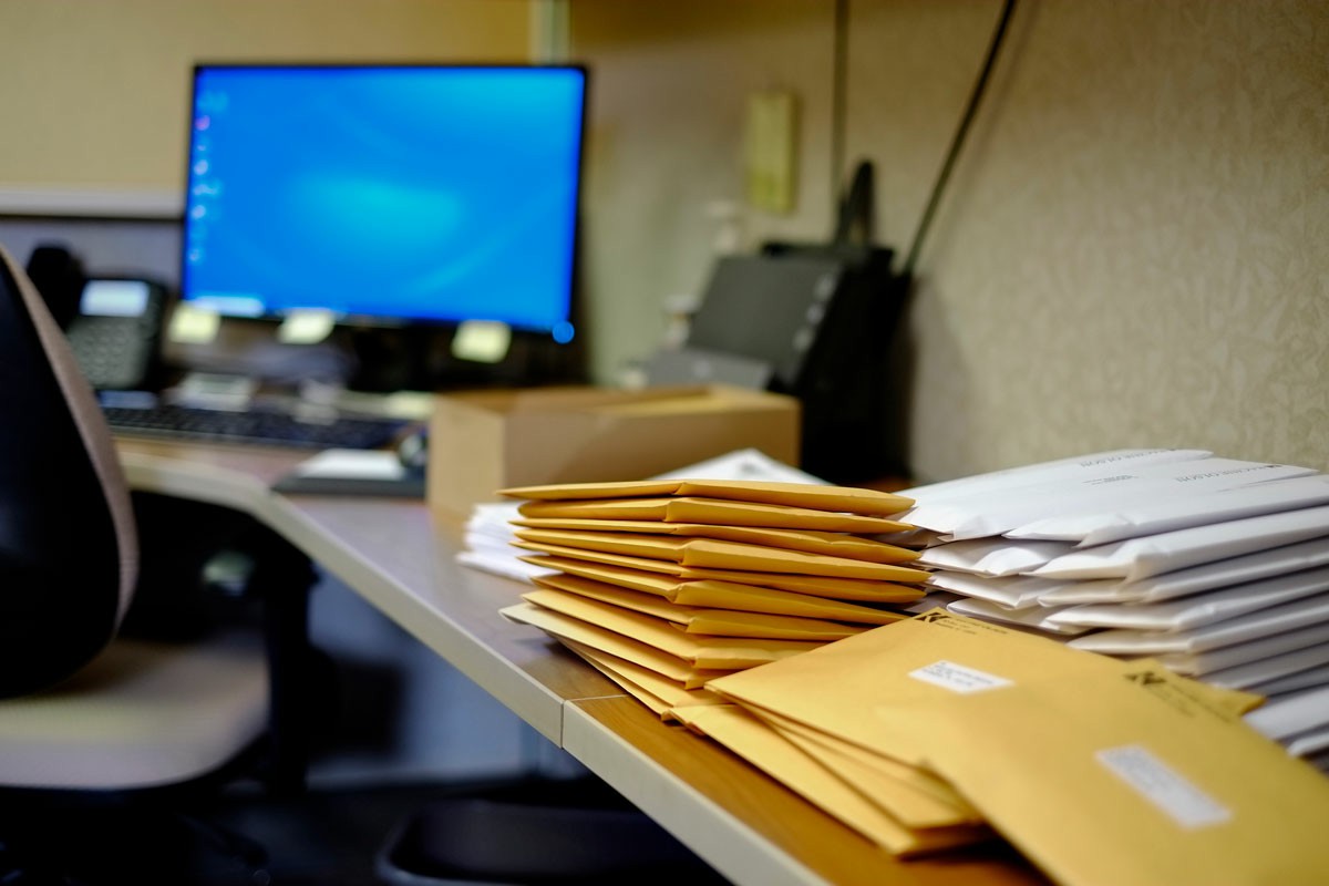 Update Your Address Avoid Missing Important Mail A desk featuring a computer monitor and a neatly stacked pile of envelopes beside it. Update Your Address Avoid Missing Important Mail