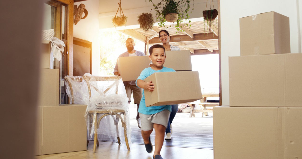 A family carrying boxes while moving into their new home, smiling and excited about their fresh start. Why Chess Moving is The Best Choice for Local Removalist Near You