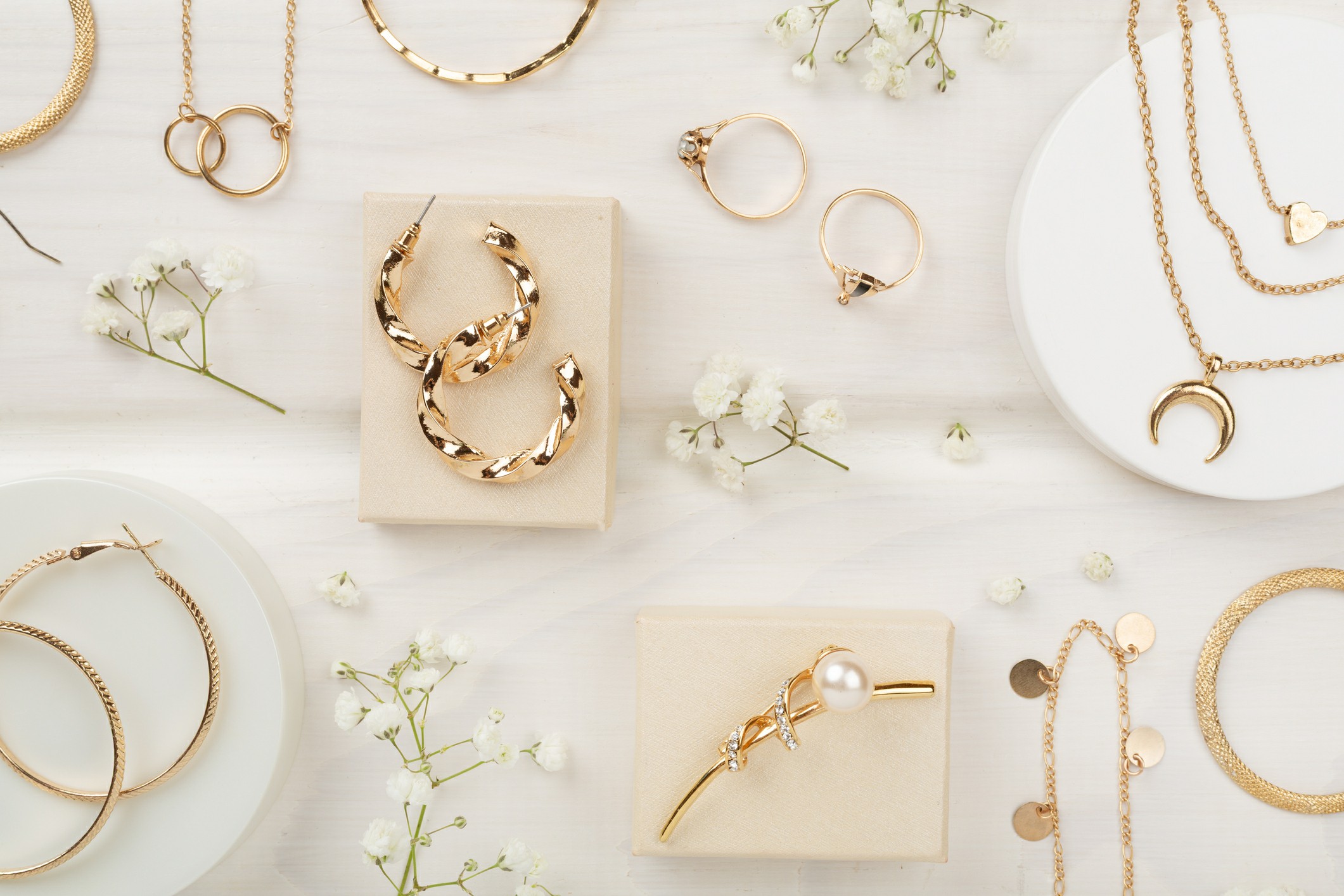 Gold jewelry displayed on a white table, surrounded by delicate flowers, highlighting its elegance and value.