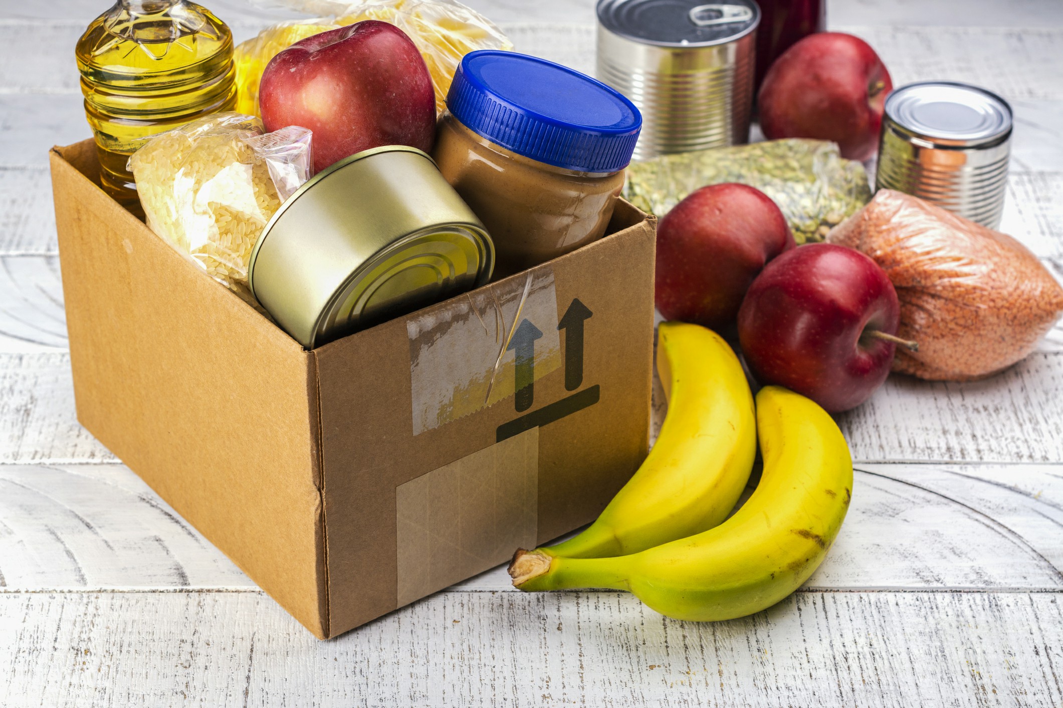 A cardboard box filled with perishable foods and organic materials, showcasing a variety of items for donation or distribution.