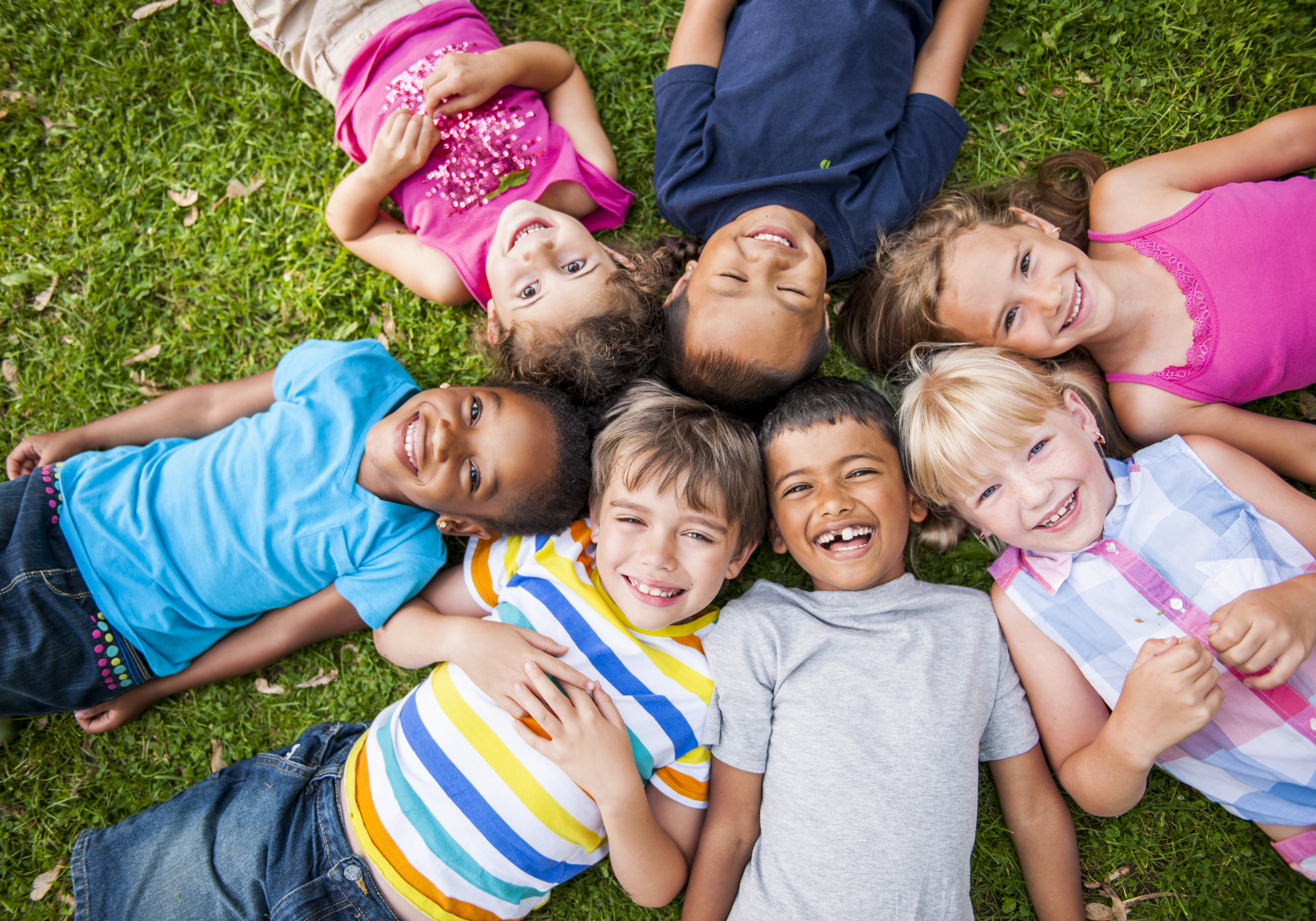Kids laying in a circle on the grass